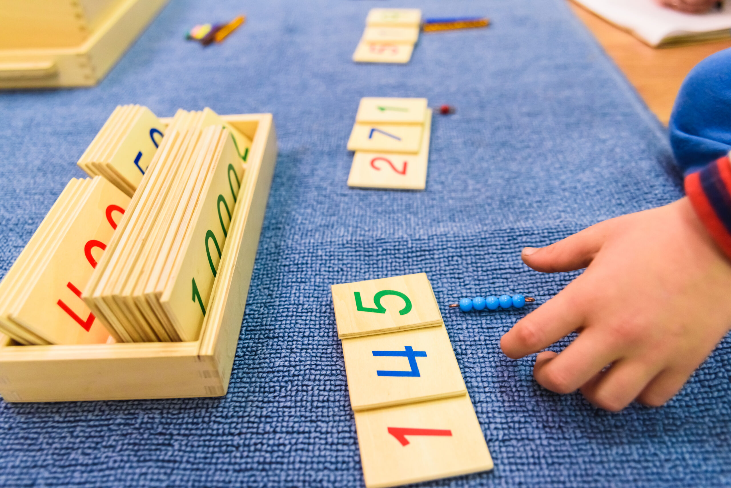 Hands of a student boy using wooden material in a montessori school.